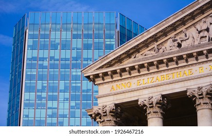 Old Vs. New: The Top Of The Stone Bank Of England Against A Background Of Blue Glass Windows Of An Office Building In The City Centre