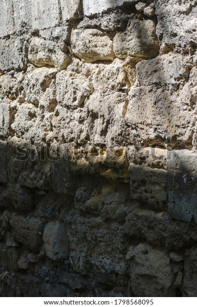 Old wall of limestone\
with grey seams, perspective view. Fragment of an old wall divided\
by sunlight and shadow. The concept of the struggle between good\
and evil.