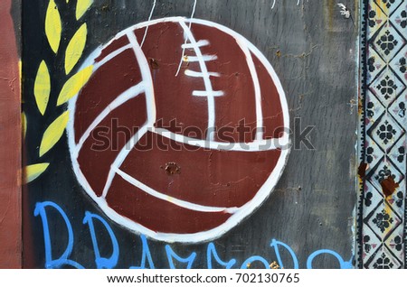 The old wall, painted in color graffiti drawing with aerosol paints. Picture of an old brown soccer ball
