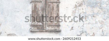 Old wall with peeling plaster. Window covered with wooden shutters. Weathered rough surface of the wall. Medieval European city. Vintage texture for background and design.