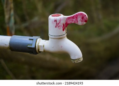 The Old Water Faucet Is White With Red Paint Spots.