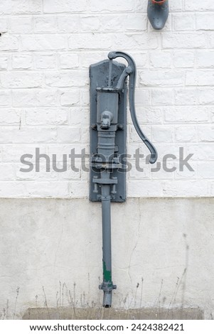 An old water pump hangs on a white wall, decoration on the wall, vintage style, the old pump serves as decoration
