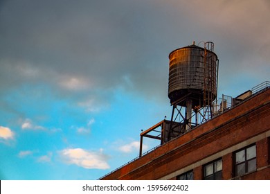 Old Water Tank Tower Over Building In Nyc New Yor City With Cloudy Sky