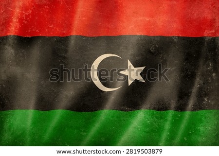 Old waving Libyan flag, worn, stained, and crumpled. Textured canva background