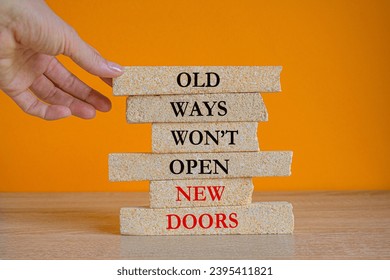 Old Ways Won't Open New Doors. Motivational quote on brick blocks on orange background. Wooden table. Businessman hand. Concept inspirational quote of the day. - Shutterstock ID 2395411821
