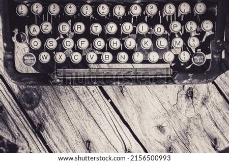 Old and weathered antique typewriter keyboard on wooden background in grayscale. Vintage and retro design. Ideal background for writing templates