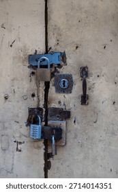 An old, weathered door is secured with multiple locks. The owner is trying to keep something safe, or perhaps keep someone out, using a variety of locking mechanisms for added security.