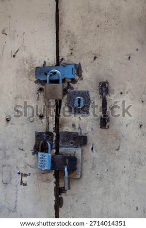 An old, weathered door is secured with multiple locks. The owner is trying to keep something safe, or perhaps keep someone out, using a variety of locking mechanisms for added security.