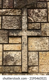 An Old Weathered Limestone Stone Church Wall With A Cross Shape Pattern.