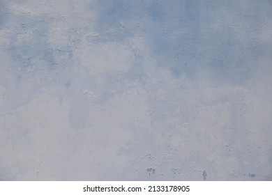 Old weathered painted wall background texture. Blue dirty peeled plaster wall with falling off flakes of paint. House wall eroded due to humidity and sunlight.
