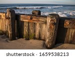 The old weathered and rusted seawall at Holgate with ocean waves in the background