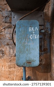 Old weathered Soviet-era electrical switch box on a brick wall with Russian text 