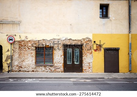 Old weathered street wall with some windows and doors