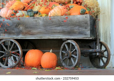 Old Weathered Wagon Filled With Many Different Varieties Of Fall Pumpkins And Squash On Rural Front Porch, Serve As A Warm Welcome To The Season's Arrival. 