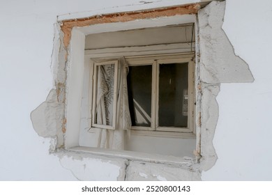 An old, weathered window in a dilapidated building, partially covered by peeling plaster. The broken frame and cracked walls evoke a sense of abandonment, making it ideal for themes of decay or urban  - Powered by Shutterstock