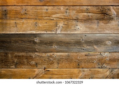 Old weathered wood surface with long boards lined up. Wooden planks on a wall or floor with grain and texture. Dark neutral brown tones with contrast.
