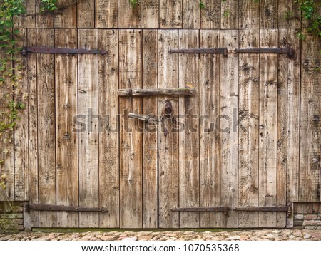 Old weathered wooden barn door with steel hinges