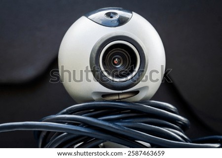 Old webcam for computer video communication, with cable, on a dark background