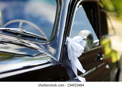 Old wedding car decorated with white ribbons