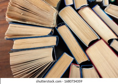 Old And Well Used Hardback Books Or Text Books In A Book Shop Or Library. Many Books Piles. Hardback Books On Wooden Table Top View. Back To School Background With Copy Space