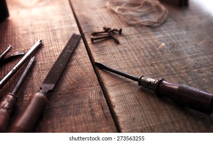 Old And Well Used Tools On A Aged Wooden Work Bench, With Incoming Light. Old Screw Driver, File On Desk. Focus On Screw Driver Tip. Intentionally Shot With Shallow Depth Of Focus And Vintage Tone.