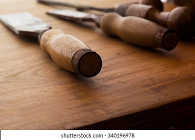 Old and well used wood carving chisels, on a old workbench. Old chisel with an oak handle. Shallow depth of field. - Powered by Shutterstock