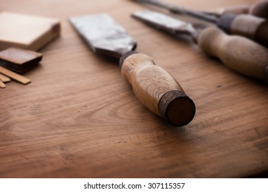 Old and well used wood working chisels, on a old workbench. Old chisel with an oak handle. Shallow depth of field.