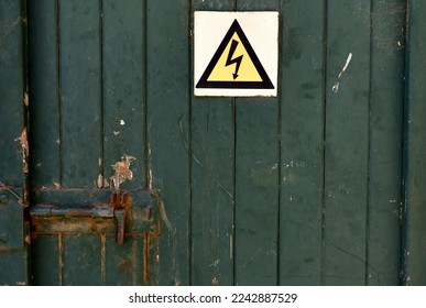 An old well-used green door guarding the electric components of the farm with a warning sign - Powered by Shutterstock