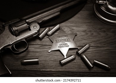 Old west. Marshals badge and revolver with cartridges on wooden table