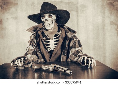 Old West Skeleton Revolver. Old West Bandit Outlaw Skeleton At A Poker Table With A Colt 45 Pistol Revolver Edited In Vintage Film Style.