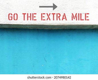 Old white blue wall with text inscription direction GO THE EXTRA MILE, concept of to do more than what people expect,	to give someone better experience, do more than one is required to do 