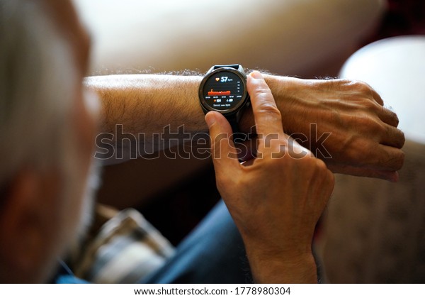 old white haired man using smart watch checking his\
cardiogram ecg