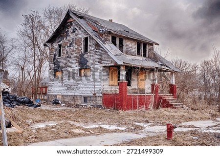 An old white house next to an empty lot in Highland Park that was damaged by fire has been abandoned and is gradually falling apart.