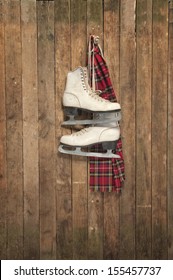 Old White Ice Skates And Scarf Hanging On A Wall