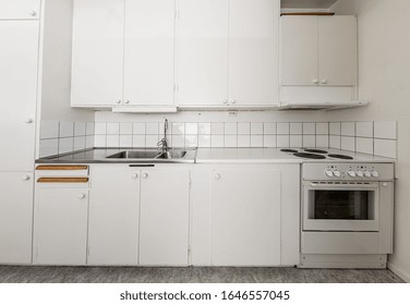 Old, White Kitchen With A Sink And Stove..