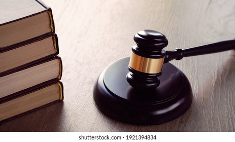 Old white phone and law hammer on wooden table with long shadows. Concept of legal advice, consultation, counseling over the phone.