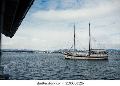 Old White Sailing Boat In The Middle Of The Calm Cold Sea In Winter. View Of Beautiful Winter Sea Coast With Fisherman Boats. Norway