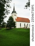 Old white stone church against the backdrop of a lawn and trees