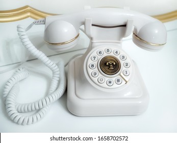 Old white telephone with rotary disc on white background
