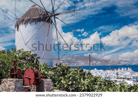 Old whitewashed typical greek windmill on the hill with cactus bushes on the foreground