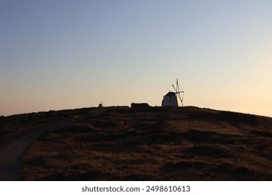 Old windmill, sunset, mountain, scenic view, historical windmill, twilight, rural landscape, windmill silhouette, evening sky, picturesque, golden hour, countryside, heritage site, traditional windmil - Powered by Shutterstock