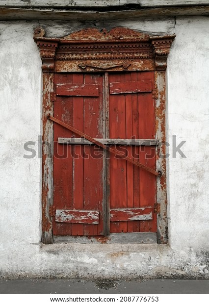 The old window is closed. Old wooden window\
sashes. Peeling red paint.