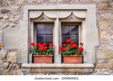 Old Window In A Medieval House Wall With Red Geranium On The Windowsill