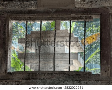 Old Window with Wire Mesh Screen and Rusty Frame in Old Concrete Wall