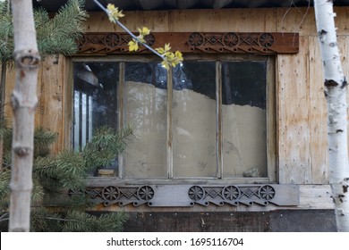An old window with wooden frames and garbage behind the glass. Old house in the woods.
