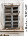 Old window with worn wooden shutters on exterior wall of an old ruined house