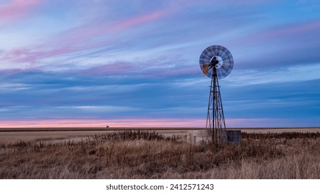 An old windpump against a blue cloudy sky during the sunset