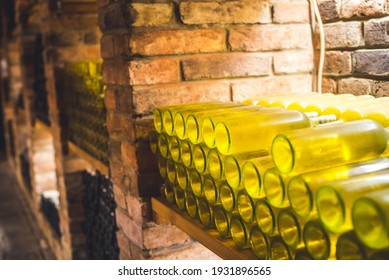 Old wine bottles dusting in an underground tratitional cellar. Small and old wine cellar with full wine bottles. Winery concept.