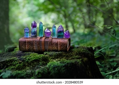 old witch book and set quartz minerals on natural forest background. Gemstones of fluorite, amethyst for Magic Crystal Ritual, Witchcraft, spiritual esoteric practice. Reiki therapy for life balance