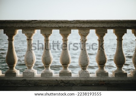 Old withered stone column railing carved by wind weather and the see in front of the blue ocean. The skyline is exactly matching the top of the white marble rail in Venice Italy.
